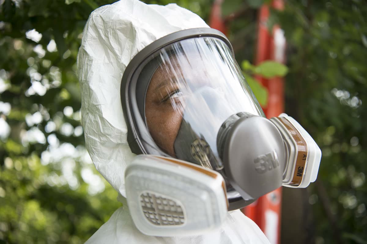 Pest control worker in protective equipment outdoors